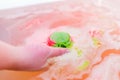 Green and red bubbling ball of bath salts in hands. Bomb for the bath. It dissolves in the hands Royalty Free Stock Photo
