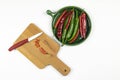 Green and red hot chilli peppers on green plate, sliced pepper on a wooden board with knife, white background, chopping board, fla Royalty Free Stock Photo