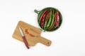 Green and red hot chilli peppers on green plate, sliced pepper on a wooden board with knife, white background, chopping board, fla Royalty Free Stock Photo