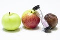 Green, red and rotten apple and time, hourglass on a white background. Young and old, concept Royalty Free Stock Photo