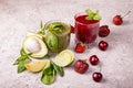 Green and red smoothie of strawberry, sweet cherry, avocado, spinach, basil, lime, green apple on gray background. Healthy diet Royalty Free Stock Photo