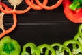 Green and red sweet pepper cut into rings on a black wooden table or kitchen board surface with workspace for text Royalty Free Stock Photo