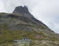 Green and red wooden mountain huts cabin at massif Trolltindene, Troll wall Trollveggen, in Romsdal valley, Norway. Cloudy white