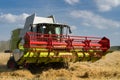 green red working harvesting combine in a field of wheat in front of a blue cloudy sky Royalty Free Stock Photo