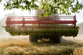 Green red working harvesting combine in a field of wheat under a Royalty Free Stock Photo