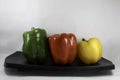 Green, red, yellow bell peppers on black platter Royalty Free Stock Photo