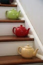 Green, red, and yellow teapots on wooden stairs Royalty Free Stock Photo