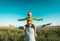 Green renewable energy concept. Happy family playing on field with wind generator turbines. Father carrying little kid Royalty Free Stock Photo