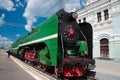 Green retro steam locomotive with red wheels arrived to the platform and building of Rizhsky Train Station Royalty Free Stock Photo