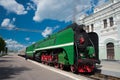 Green retro steam locomotive with red wheels coming to the platform and building of Rizhsky Train Station Royalty Free Stock Photo