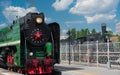 Green retro steam locomotive with red wheels staying at the platform with black retro train Royalty Free Stock Photo