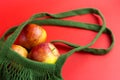 Green reusable shopping string bag with Fresh apples on red background. Zero waste concept. No plastic Royalty Free Stock Photo