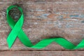 Green ribbon. Scoliosis, Mental health and other, awareness symbo on the wooden background with copy space Royalty Free Stock Photo