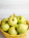 Green ripe apples in a wicker yellow basket