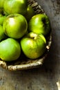 Green ripe organic bio apples, local produce, in rustic wicker basket on weathered wood table, harvest Royalty Free Stock Photo