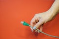 Green RJ45 network connector on a red background in well-groomed female hands Royalty Free Stock Photo