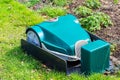 Green robotic Lawnmower charging on grass