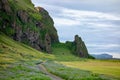 The green rocky hill and a rock above Vik i Myrdal village in Southern Iceland during beautiful sunset with shadows