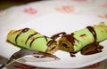 Green rolled crepe stuffed with chocolate cut in two pieces