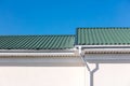 Green rooftop of newly built house white metal gutter pipes and downspout on blue sky background Royalty Free Stock Photo