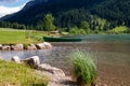 .Green rowboat on the beach of a romantic mountain lake with stones in the foreground and mountains in the background Royalty Free Stock Photo