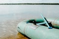Green rubber inflatable boat with paddle on shore of lake on sunny summer day outdoors, close-up Royalty Free Stock Photo