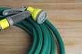 Green rubber watering hose with nozzle on wooden surface, closeup Royalty Free Stock Photo