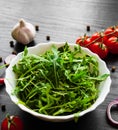 Rucola fresh salad in white bowl on dark wooden background Royalty Free Stock Photo