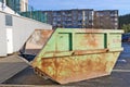 Green rusty aged steel container for construction and industrial waste installed in a old residential area