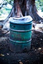 Rusty garbage can in front of a tree in a public park Royalty Free Stock Photo