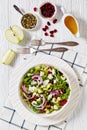 Green Salad with Apples, Goat Cheese, Cranberries, Red Onion and green pumpkin seeds in white bowl on white wood table