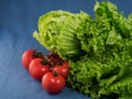 Green salad, Chinese cabbage and fresh tomatoes on a blue textile background, close-up. Selective focus on lettuce leaves. Royalty Free Stock Photo