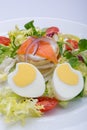 Green salad with eggs in the shape of a heart, salmon, cherry tomatoes