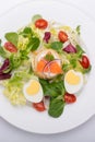 Green salad with eggs in the shape of a heart, salmon, cherry tomatoes