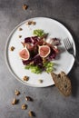 Green salad with figs on white plate and grey background.