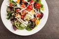 Green salad topped with beans, tomato and cheese on a plate cropped off shot Royalty Free Stock Photo