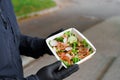 Green salad with veal and vagatables. Safety delivery with mask and black medical gloves at quarantine. Salad in eco