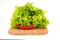 green salad on a wooden board and chili peppers on a white background Royalty Free Stock Photo