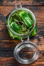 Green salted cucumbers in a glass jar. Canned vegetables. Dark Wooden background. Top view