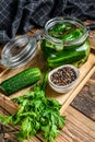 Green salted cucumbers in a glass jar. Wooden background. Top view