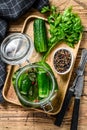 Green salted cucumbers in a glass jar. Wooden background. Top view