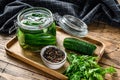 Green salted cucumbers in a glass jar. Wooden background. Top view