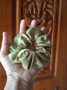 Green satin scrunchie with balinese carved wood as background