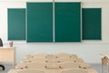 Green school board in the classroom with no pupils. in the foreground are desks and chairs. close-up Royalty Free Stock Photo