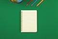 Green school table with blank lined notebook and pencils top view photo with copy space Royalty Free Stock Photo