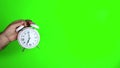 Green screen chroma key footage of a males hand holding and old fashioned alarm clock saying 7pm or 7am