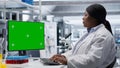 Green screen desktop next to black woman researcher performs bio science Royalty Free Stock Photo