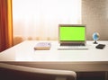 Green screen laptop computer sitting on a home work desk next to notebook, spring flowers and world globe stand. Royalty Free Stock Photo