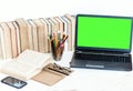 Green screen laptop, pile if books, notebook, smartphone, glasses and pencils in holder on white table, education concept