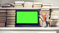 Green screen laptop, stack of books, notebooks and pencils on white table, education office concept background Royalty Free Stock Photo